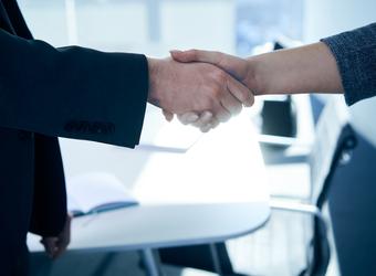 Two people in an office shaking hands.